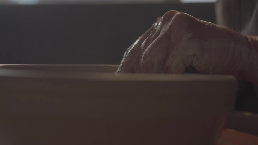 A person makes a bowl out of clay
