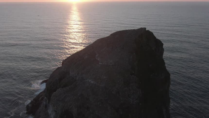 Waves hit the large boulder sticking out of the ocean