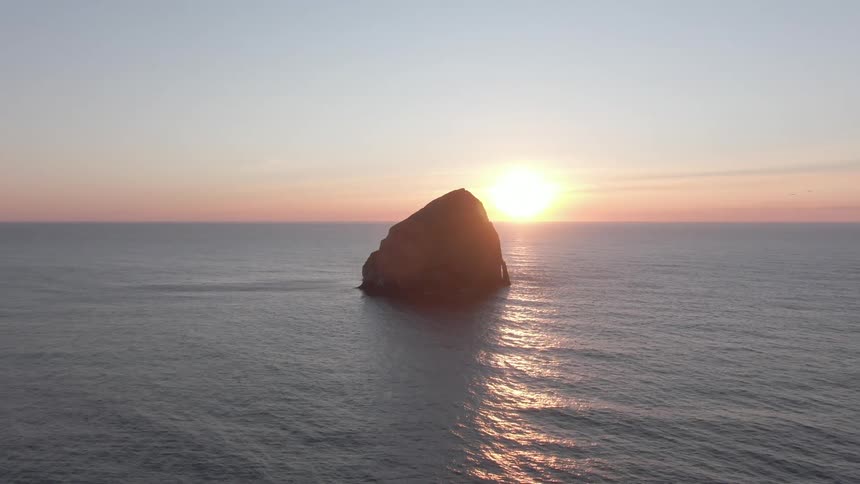 A large boulder is sticking up out of the ocean