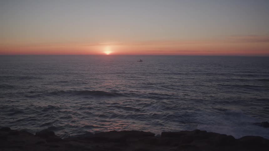 The sun is rising on the rocky shore