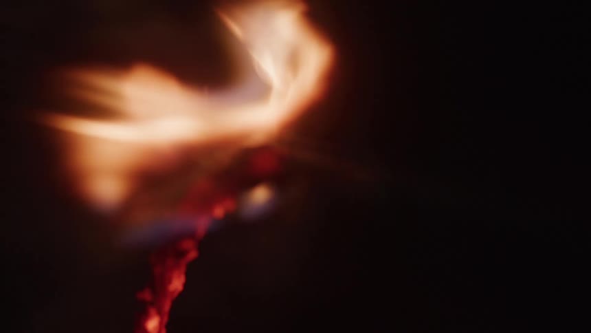 Fire burns through a rope at nighttime