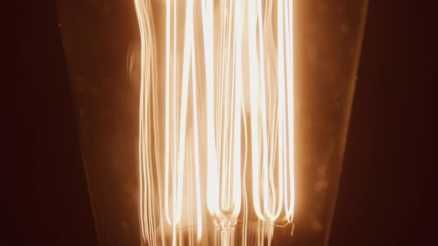 Close up detail of a light bulb turning on against a dark background