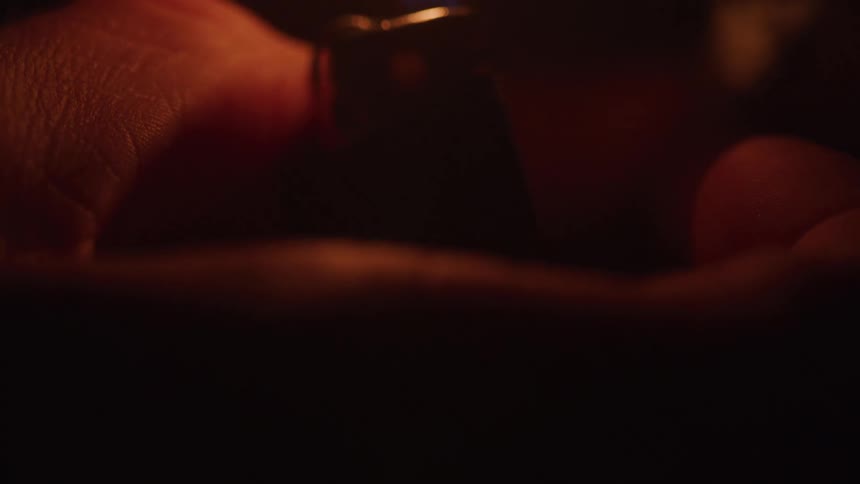 Close up of a persons hand as they put on a hand lighter in the dark
