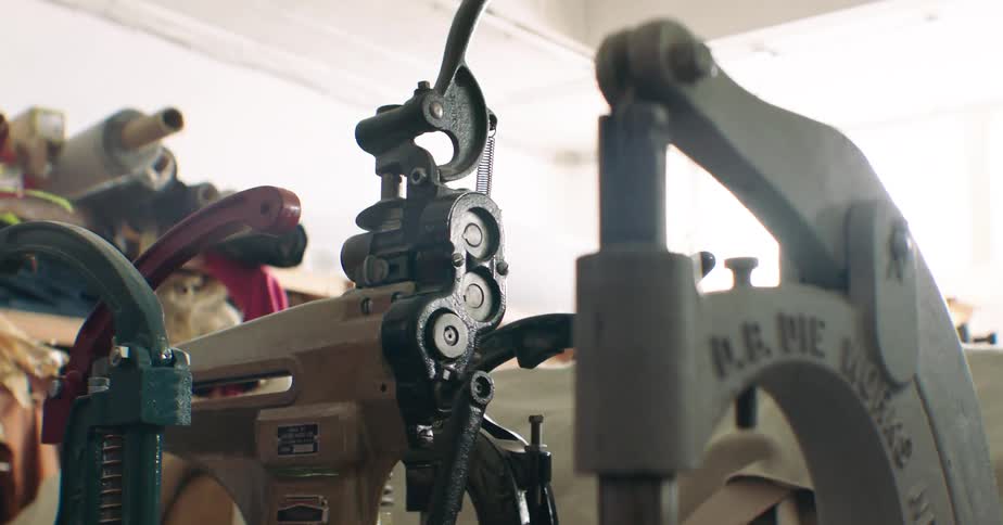 Manual machine inside a factory with rolls of fabric in the background