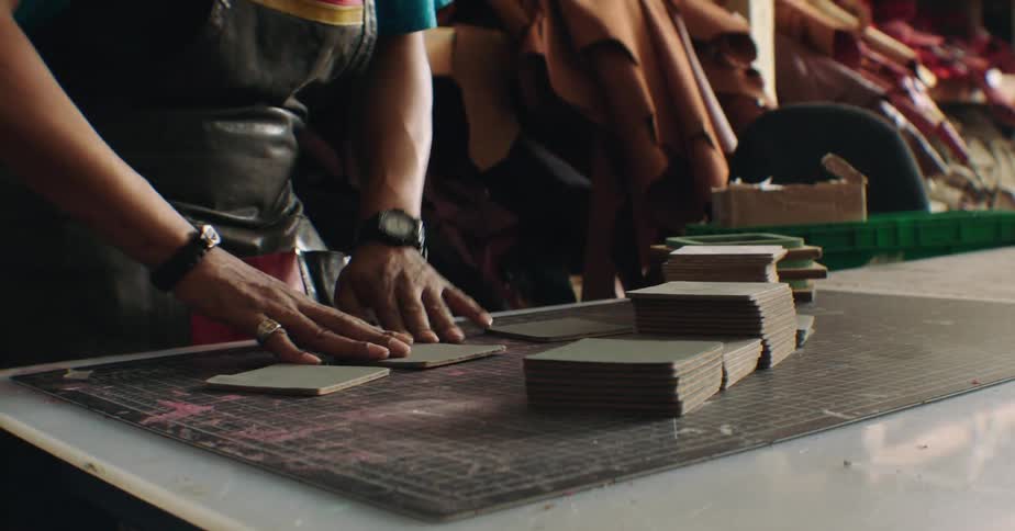 Man in apron working with leather fabrics at a table