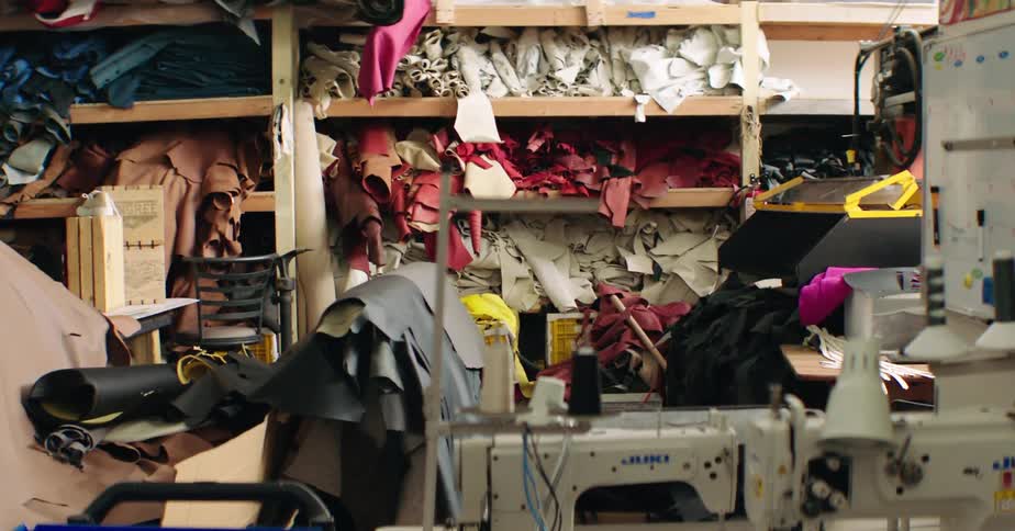 A fashion designers shop contains sewing machines and a shelf filled with fabrics