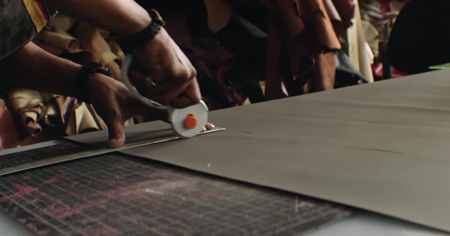 A workman cuts fabric with a rotary cutter in a workshop