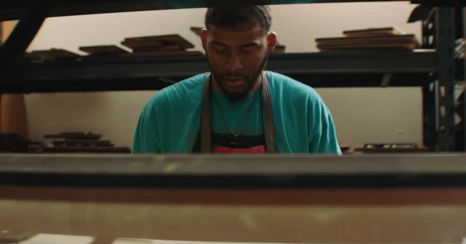 Man in apron working in indoor space with shelves
