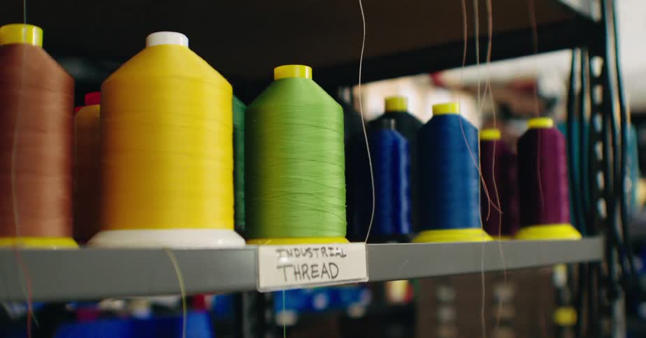 Various shades of colored industrial thread on a metal shelf