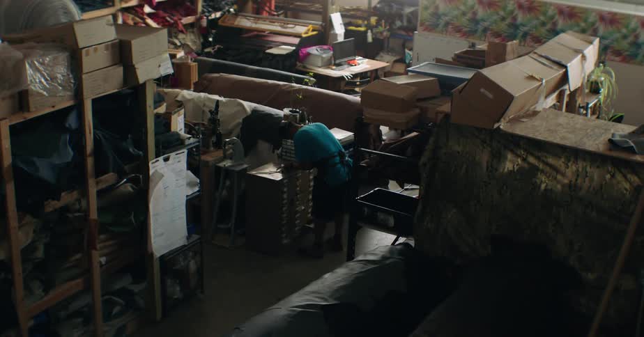 A shoemaker works on the shoemaking process inside a workshop around midday
