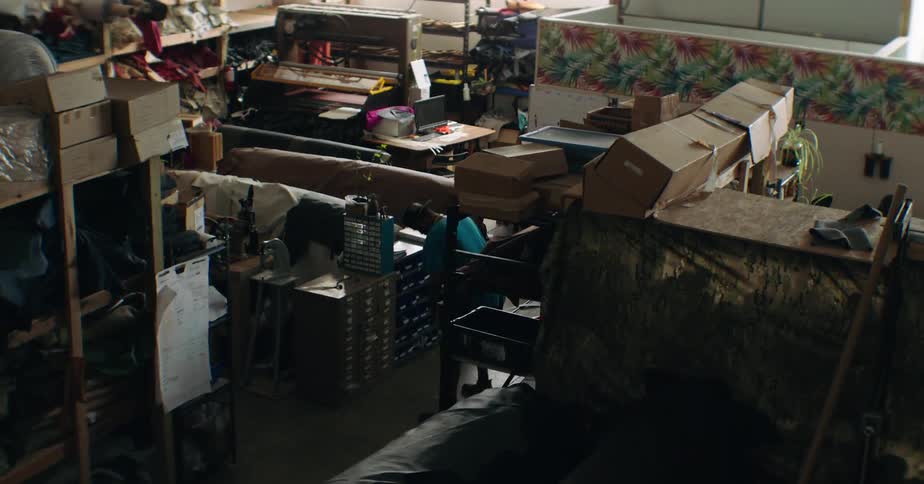 A cluttered workshop or storage room is filled with shelves boxes tools and equipment creating a busy and somewhat chaotic atmosphere