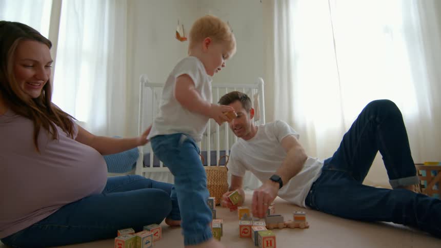 A family plays with blocks together on the floor of a nursery