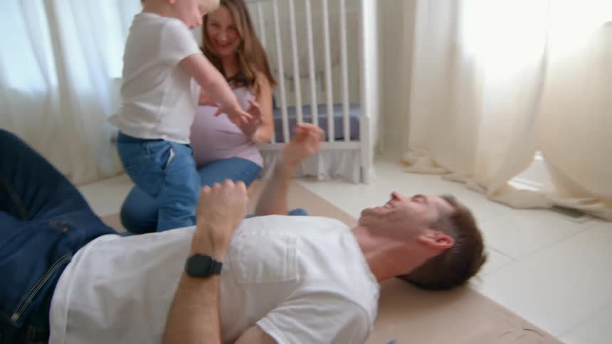 Little boy in a room playing with his father and pregnant mother next to him