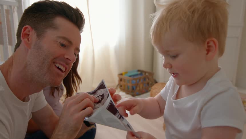 Father next to pregnant wife showing other little son pregnancy ultrasound