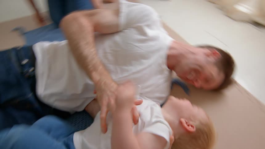 Father playing with his little son in the room next to his pregnant mother