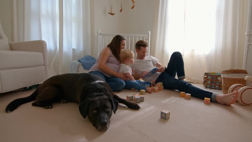 Family sitting in bedroom with large dog lying next to them