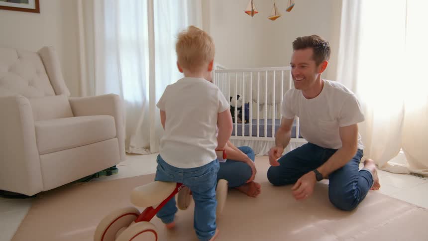 A father tickles his son on the toy vehicle