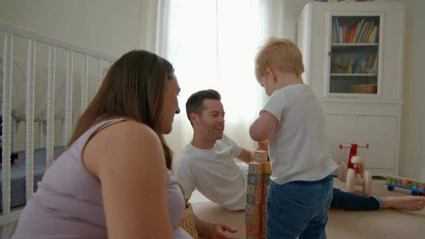 The boy stacks the blocks as his family watches