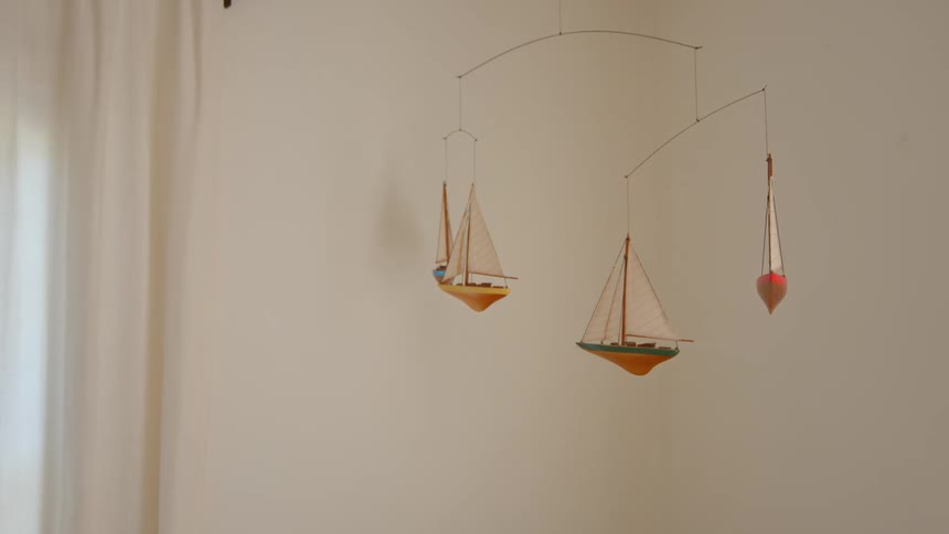 Boats hang from the baby mobile