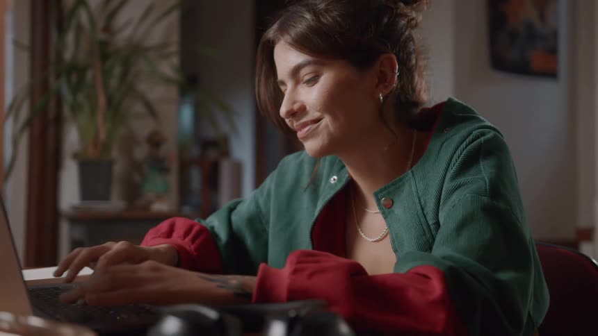 The woman smiles while using her laptop at home