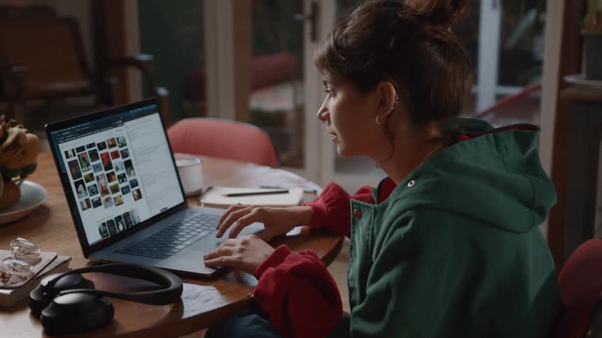 Young woman sitting at a table and interacting with a laptop