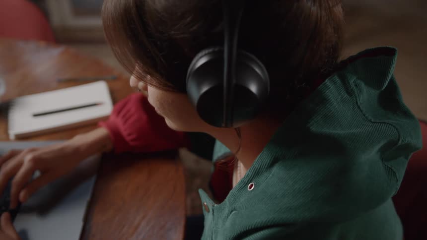 Woman with headphones sitting typing on a laptop