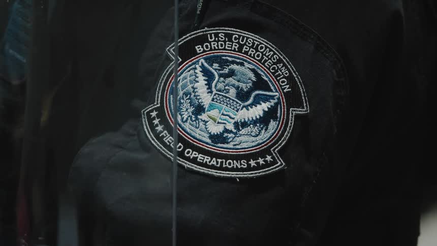 The customs agent is holding a riot shield