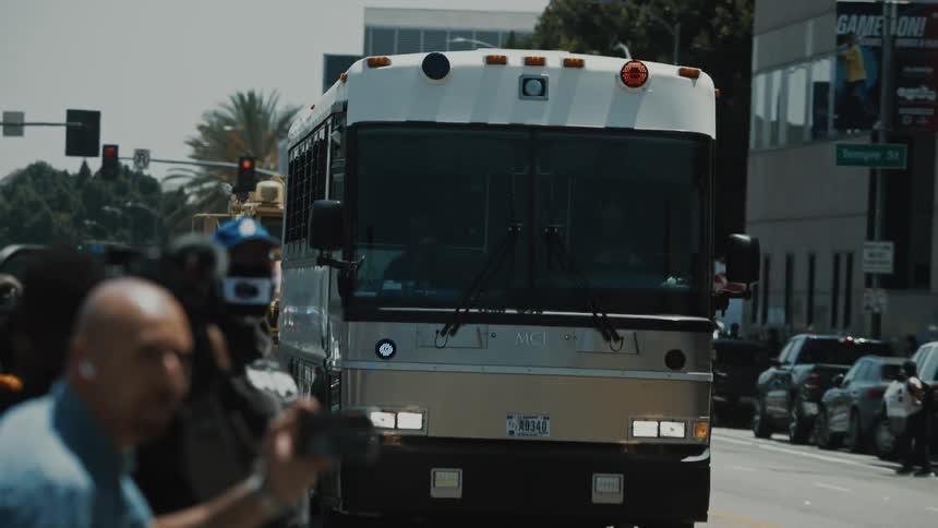 A US Marshalls bus containing immigration detainees arrive as protestors, reporters, and riot police watch
