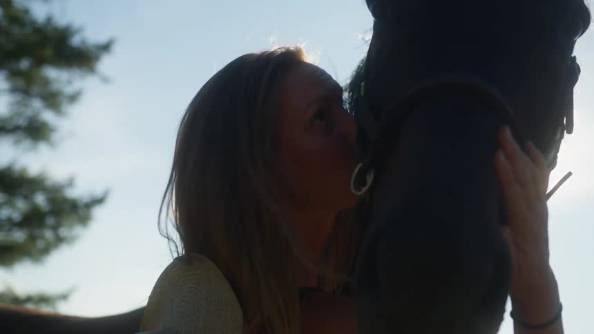 A woman gives a kiss to a horse