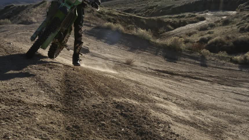 A person rides a dirt bike around a curve on a dirt track