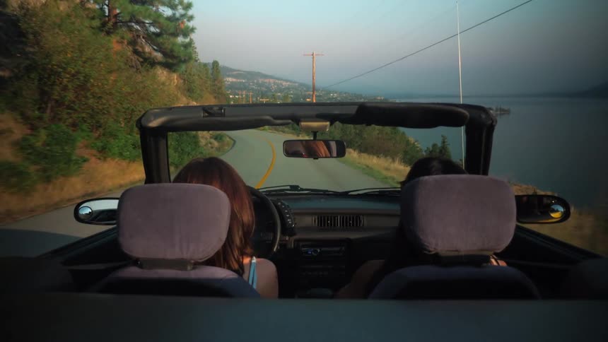 A couple woman driving down a road