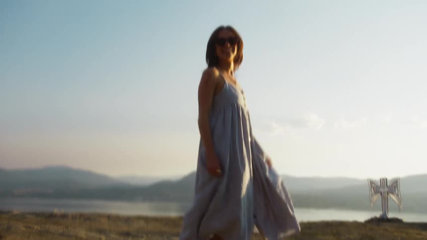 The woman runs and spins around by the lake