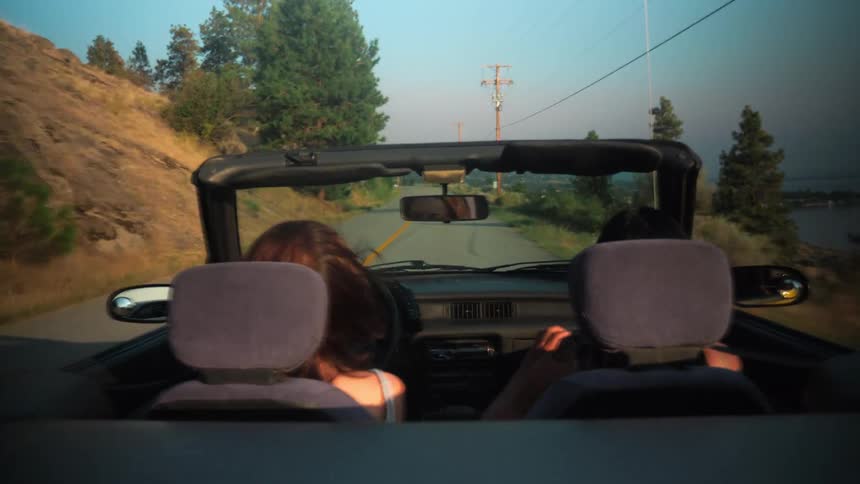 A woman takes a photo of her friend as she drives