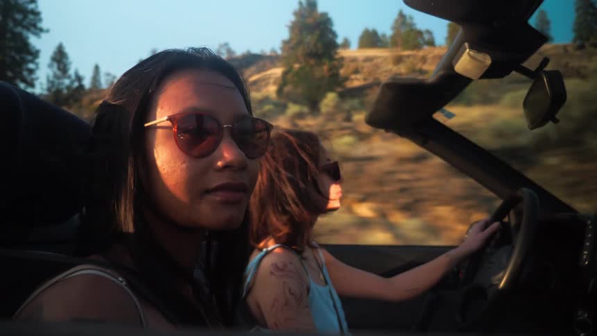 Two women driving a vehicle on the road