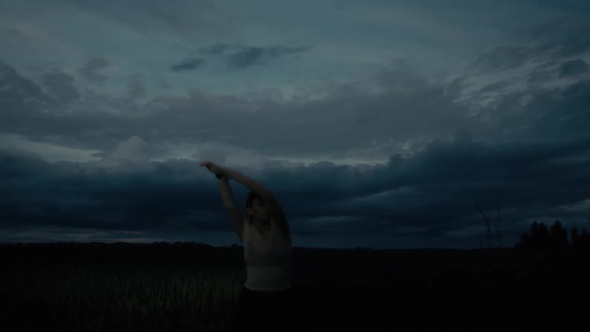 A woman is stretching on the dark field