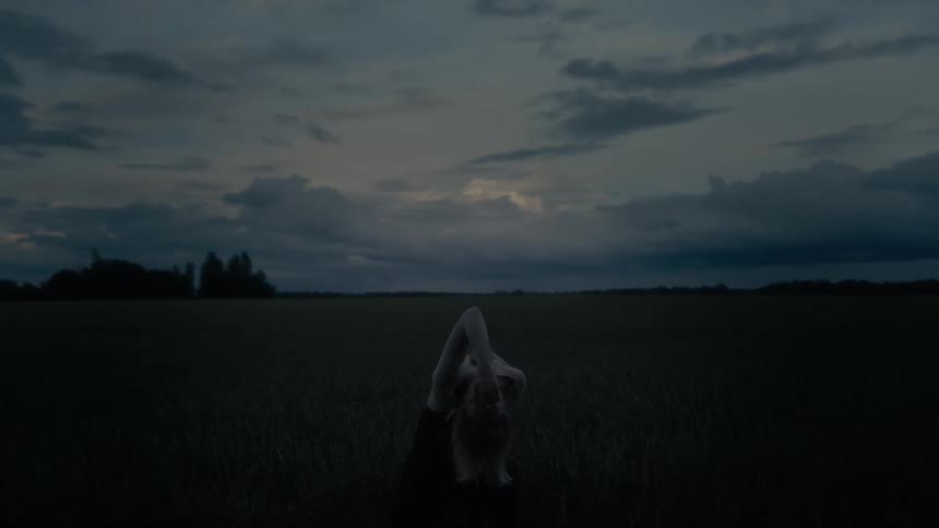 Woman in a solo performance in a green field at dawn