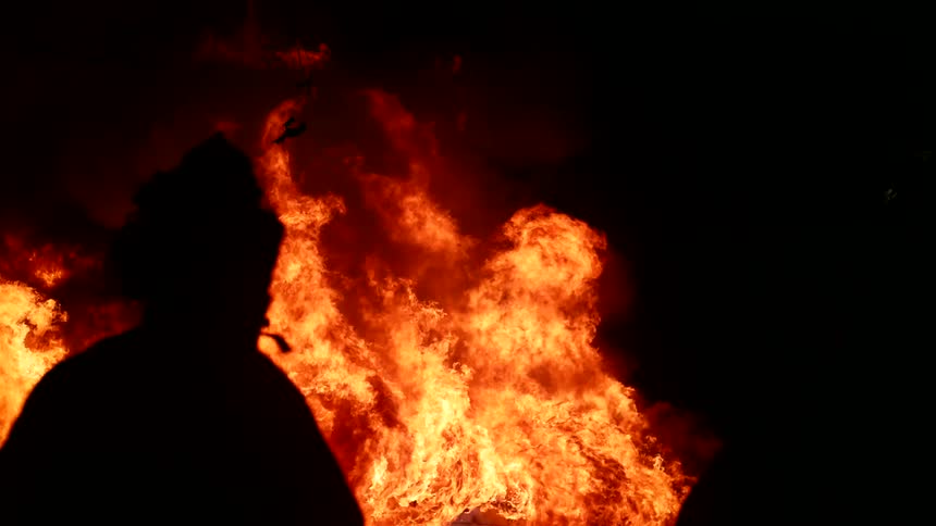 Silhouette of firefighters working on a fire at night