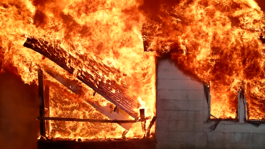 A house engulfed in intense explosion of flames at night