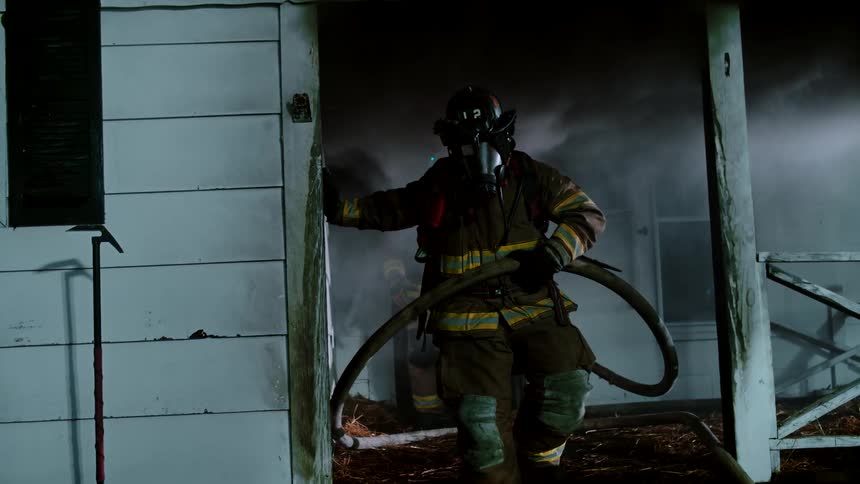 Firefighters carry a hose out of the burned home