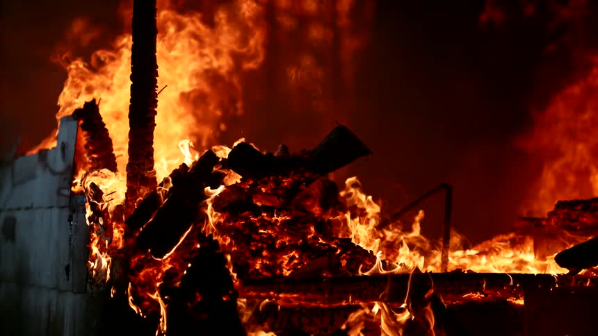 Flames rise in a building totally engulfed in a blazing fire in the darkness