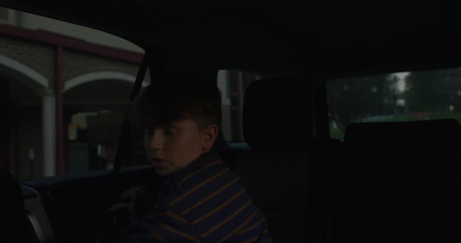 The boy gets out of the car and walks towards school
