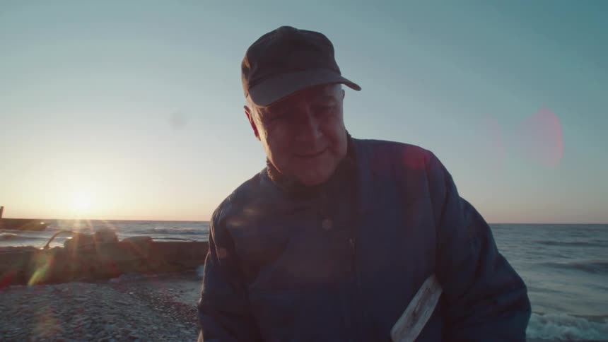 Man in cap holding a branch in beach environment