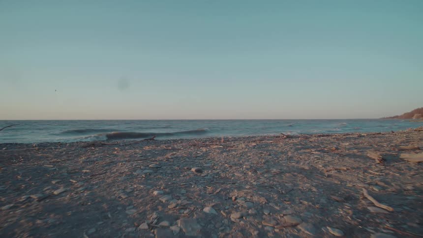 A rocky shoreline stretches toward a calm sea under a clear evening sky