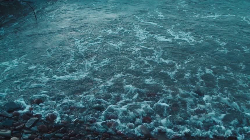 Waves gently roll onto a rocky shoreline in a calm coastal scene