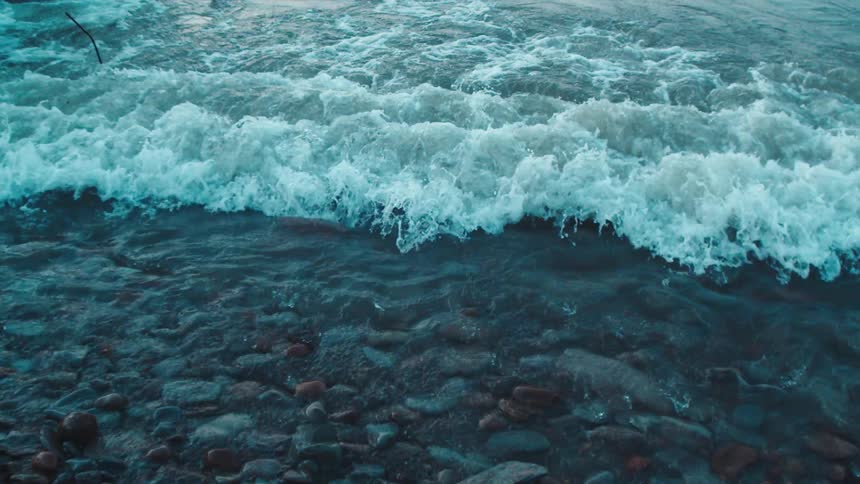 Waves splash as they roll in to shore and over the rocks along the coast