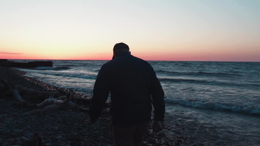 The man walks on the beach at sunrise