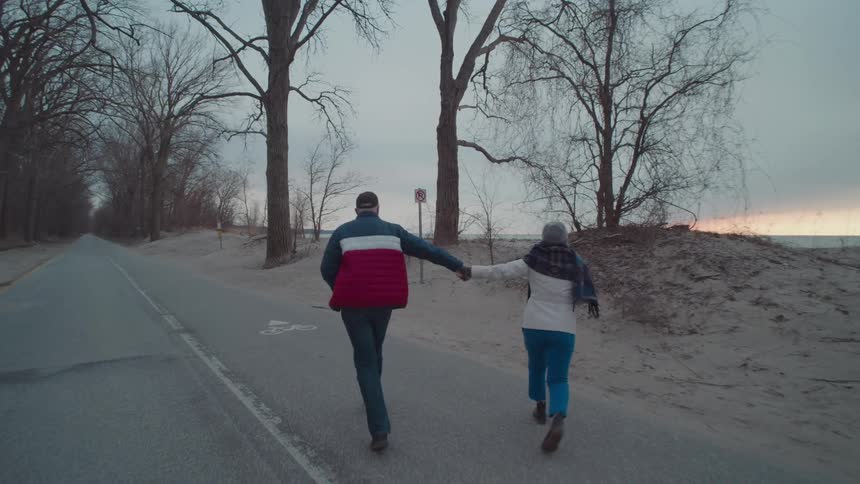 Couple holding hands and walking along the beach on a winter day