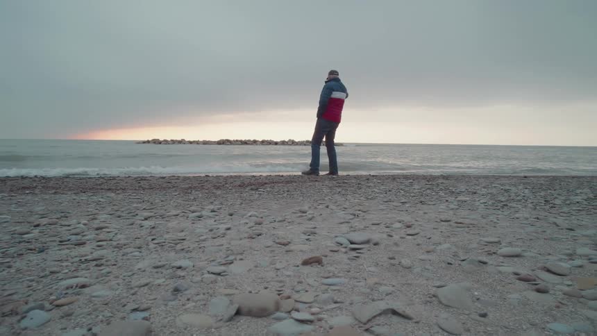 A man and woman walk along the beach