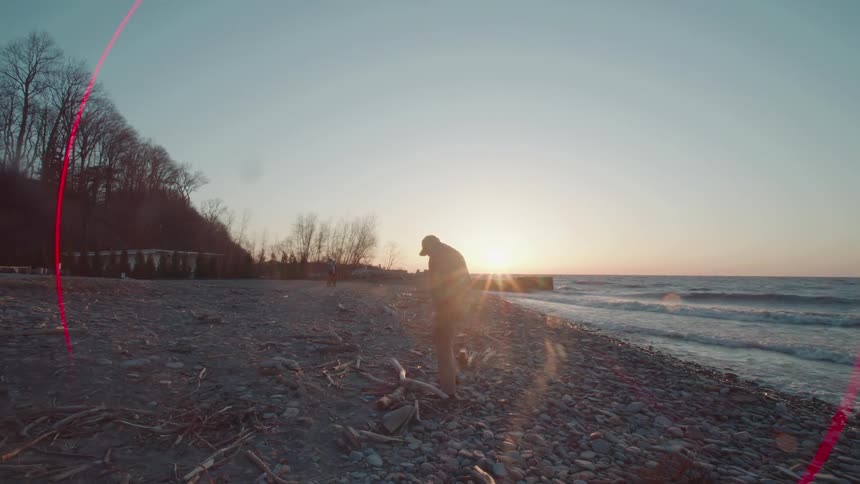 Silhouette of a person walking among rocks on the seashore of a beach