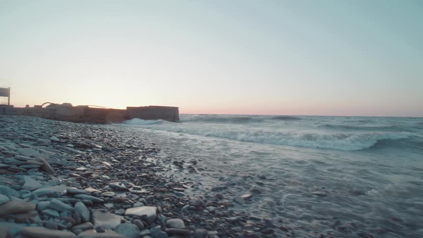 Rocks and stones cover the beach as waves roll in to shore